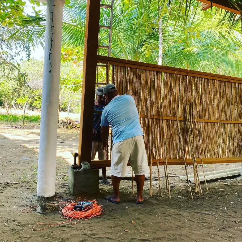 Local craftsman fitting cane walls on a new cabana at Bliss Beach