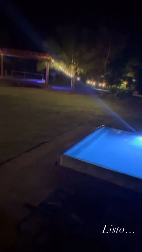 The pool glowing blue at night under the string lights
