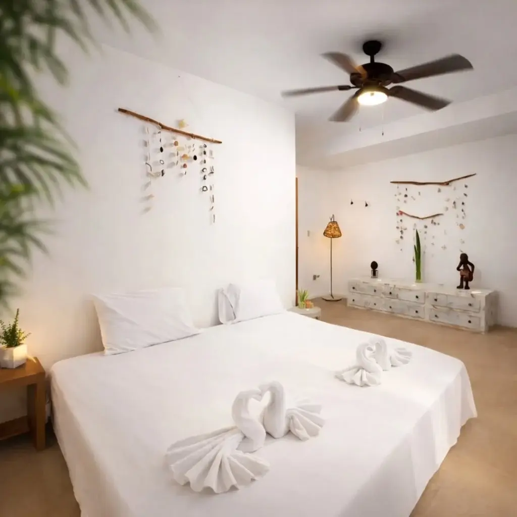 White garden room with towel swans on the bed and shell mobiles