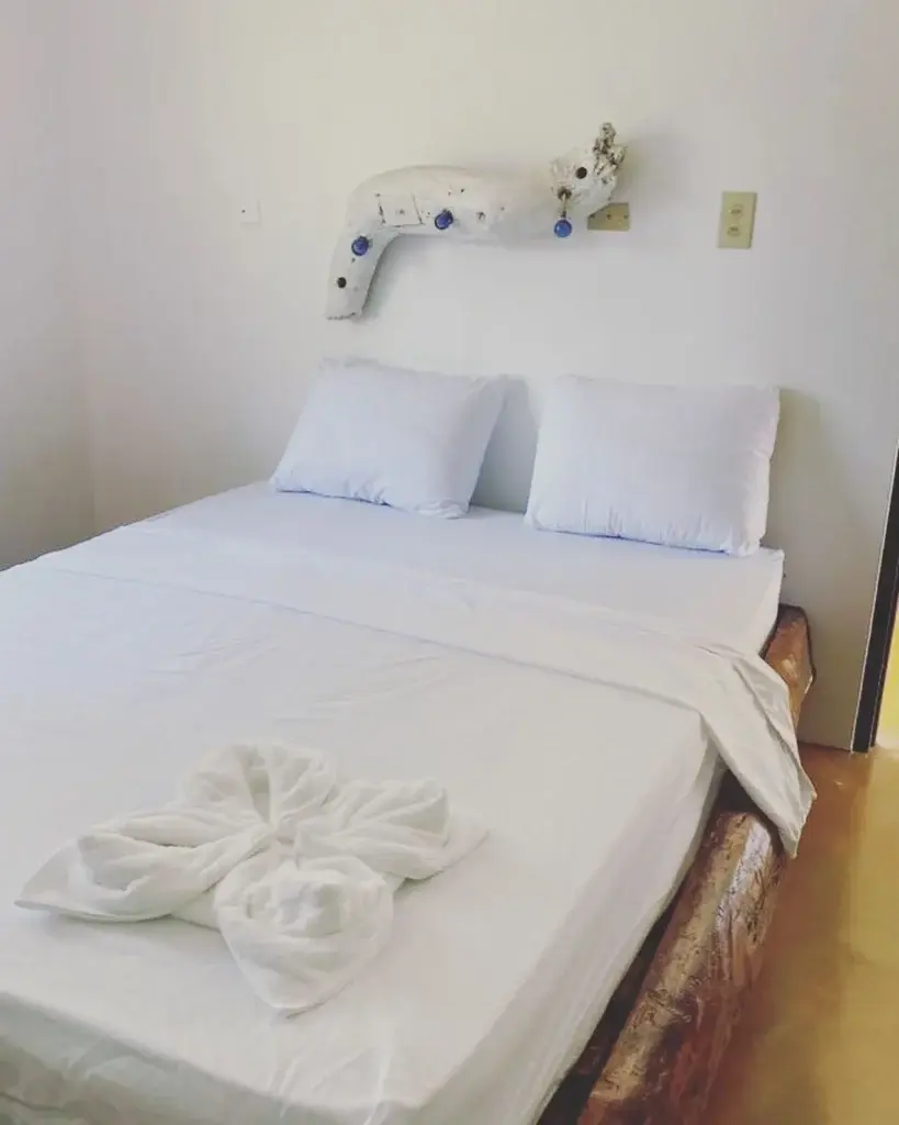 Freshly made bed with a towel flower and a ceramic fish