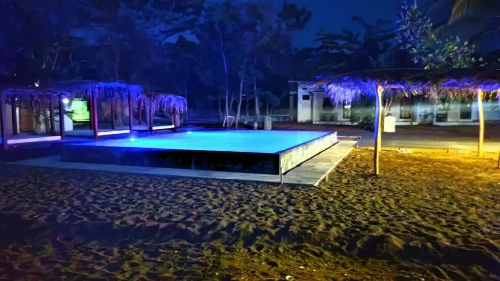 Pool and palapas lit blue at night on the Bliss Beats venue grounds