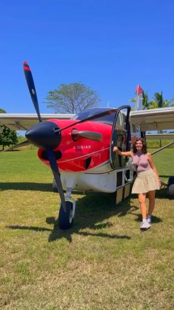 Pasajero bajando de una avioneta chárter Kodiak roja y blanca en la pista de Lago Bay