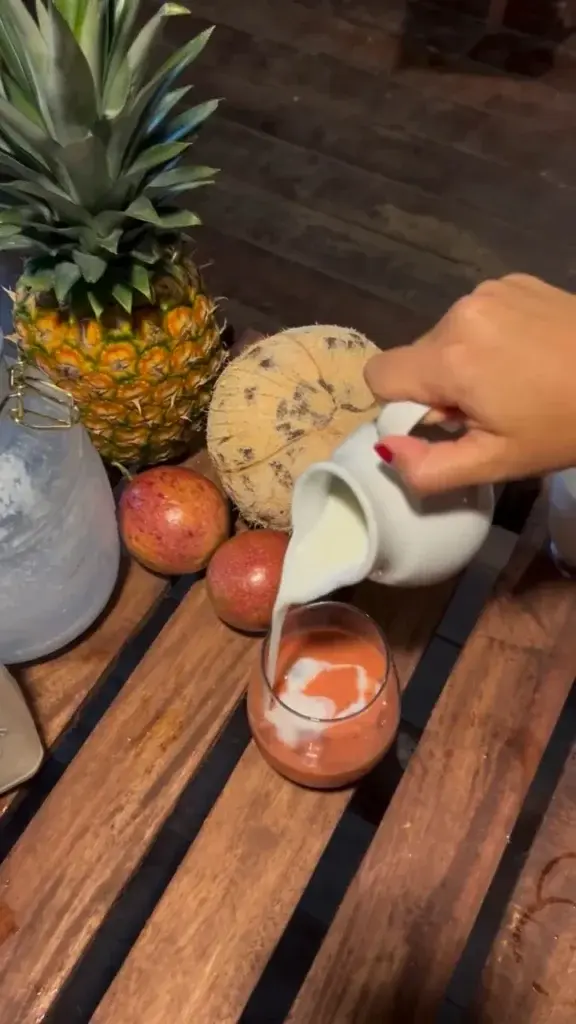 Homemade kefir being poured with pineapple and passion fruit