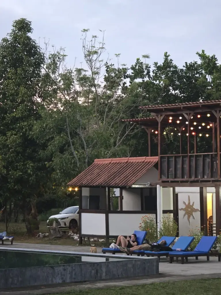 Guests relaxing by the pool beneath the lit lodge in the evening