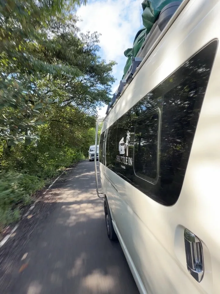 Costado de una van de shuttle en una carretera arbolada