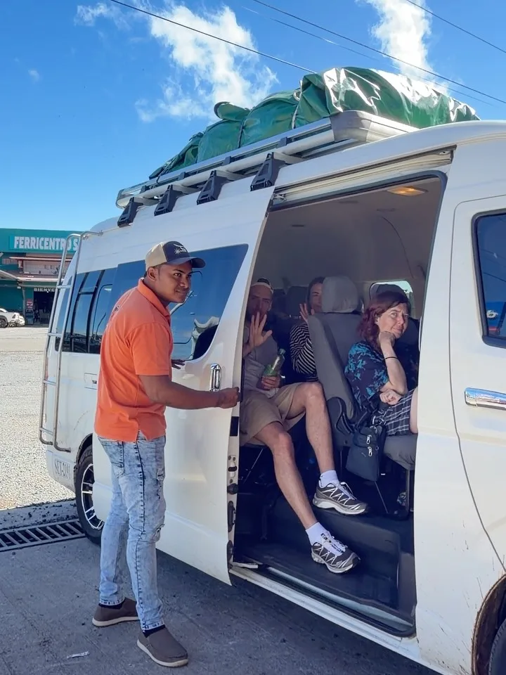 Conductor ayudando a los pasajeros a subir a una van de shuttle