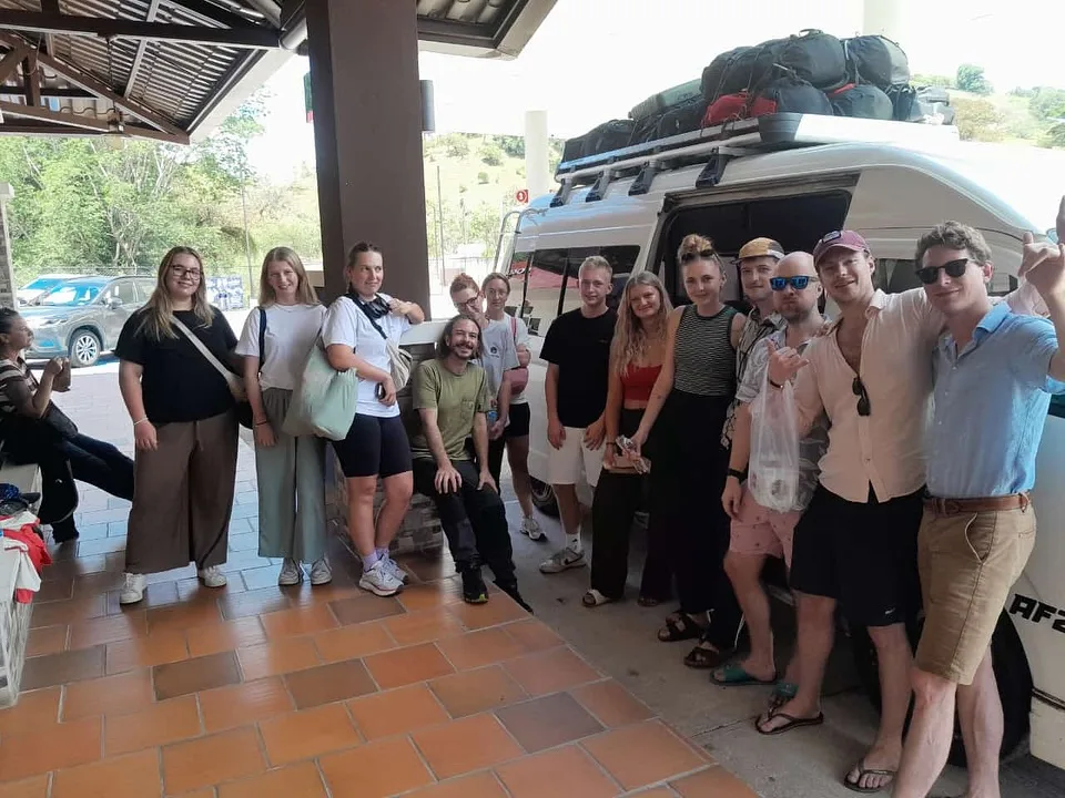 Gran grupo de viajeros con su van de shuttle y equipaje en el techo