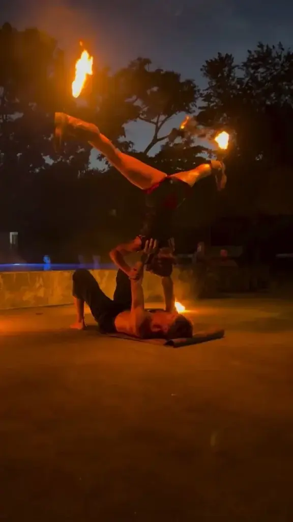 Performer balanced overhead in a split during the fire show