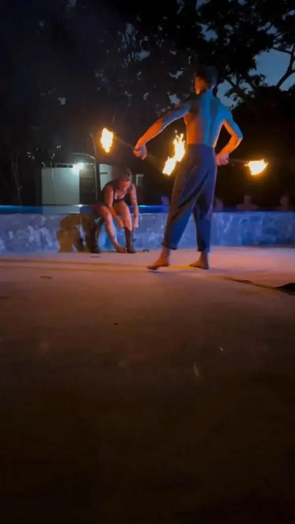 Two performers with fire staffs on the pool deck