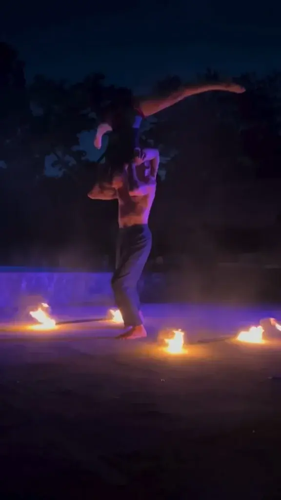 Performer dancing inside a ring of small fires on the deck