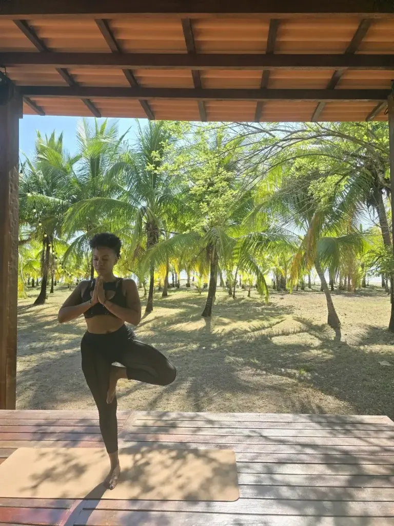 Tree pose on the yoga deck with the palm grove behind