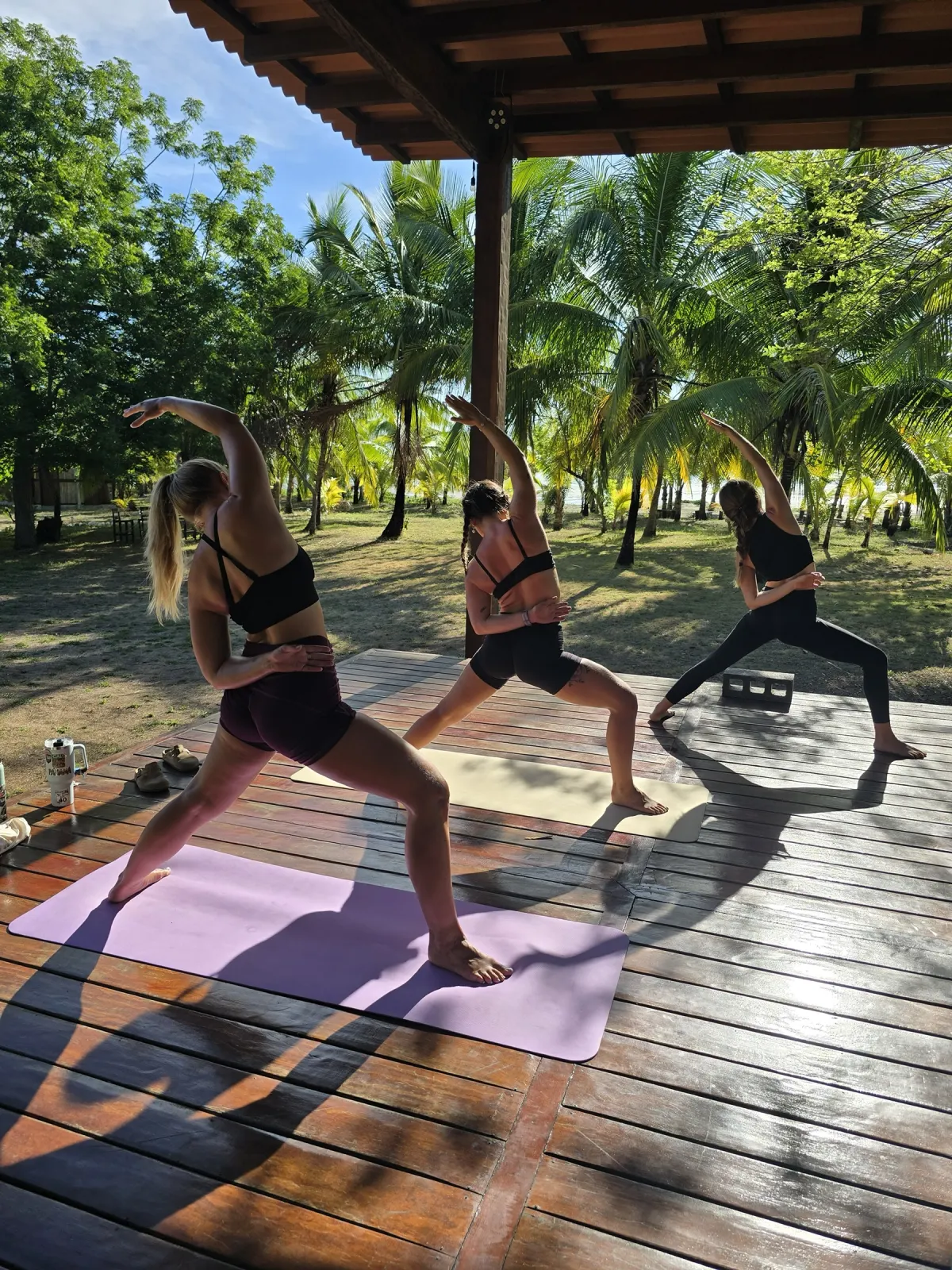 Three guests flowing through warrior poses on the yoga deck